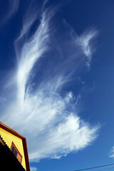 A cirrus cloud over the roof of a house.