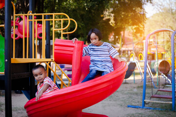 Joyful Children Sliding Down A Playground Slide During A Sunny Afternoon