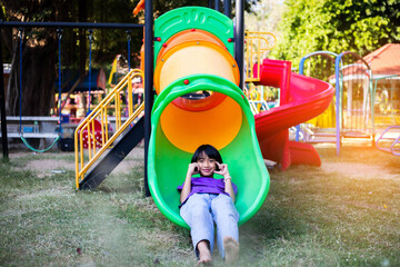 Joyful Children Sliding Down A Playground Slide During A Sunny Afternoon