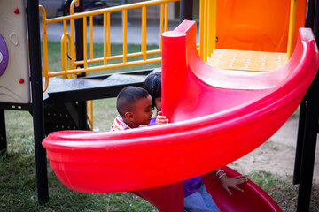 Joyful Children Sliding Down A Playground Slide During A Sunny Afternoon