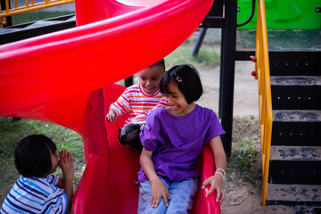 Joyful Children Sliding Down A Playground Slide During A Sunny Afternoon