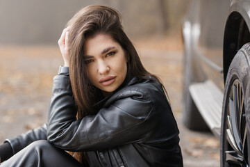 Stylish Woman in Leather Jacket Posing Beside Car in Autumn Setting