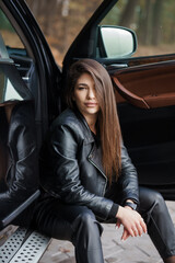 Stylish Young Woman in Leather Outfit Posing by Car