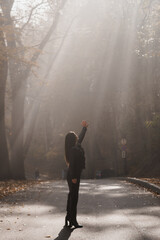 Ethereal Encounter: A Woman Reaching for Light in a Misty Forest Path