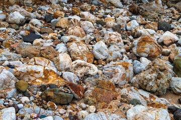 Ancient rocks pebbles with different textures on Red Island containing minerals and metals. Stone background.