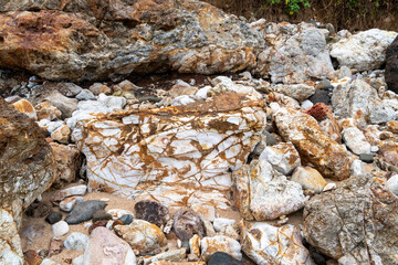 Ancient rocks pebbles with different textures on Red Island containing minerals and metals. Stone background.