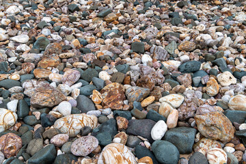 Ancient rocks pebbles with different textures on Red Island containing minerals and metals. Stone background.