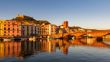 Panoramic view of the picturesque town of Bosa with its colorful houses reflected in the Temo River at golden hour. Sardinia, Italy.