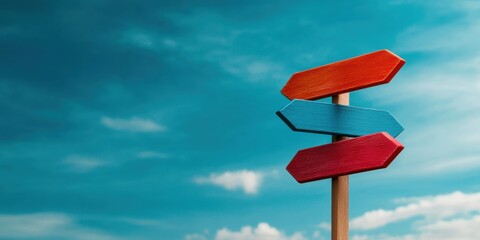 A colorful wooden signpost with three arrows pointing in different directions stands against a bright blue sky, symbolizing choices and adventure in life.