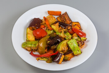 Different baked vegetables on dish on a gray background