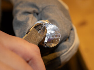 Cutting a burr of a solid aluminum part with a side cutter. Manual deburring of a sharp edge of...