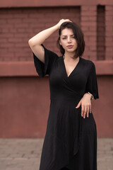 Portrait of a young beautiful dark-haired girl in summer clothes in an urban environment.