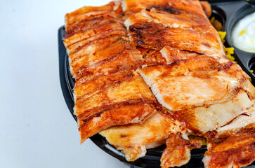 Close up of chicken shawarma meal with lettuce, tomato and onion on white background.
