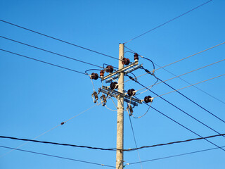 Network of electric cables on electric poles with a clear blue sky in the afternoon
