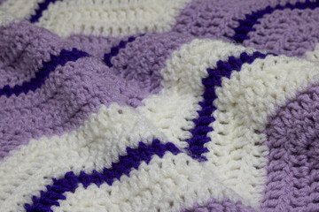 close-up of grandma's retro zigzag striped blanket, in white, lilac or lavender and royal purple,...