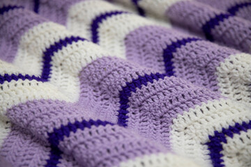 close-up of grandma's retro zigzag striped blanket, in white, lilac or lavender and royal purple, crocheted or knitted, grandma's house, cozy and warm, rippling