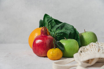 Still life of fruits and spinach leaves on a table covered with a linen tablecloth on a gray background with copy space