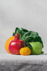 Still life of fruits and spinach leaves on a table covered with a linen tablecloth on a gray background with copy space