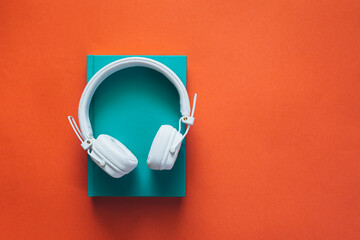 Headphones and a book on an orange background isolated, audiobook concept.