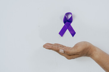 Hand holding purple ribbon on white background. World Cancer Day.