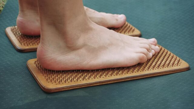 Close-up of feet on a wooden acupressure sadhu board outdoors, providing natural foot therapy and relaxation.
