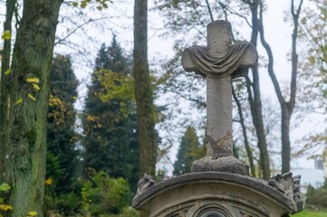 Obraz premium Stone cross standing on tombstone in lush cemetery