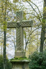 Stone cross standing in cemetery representing faith and remembrance