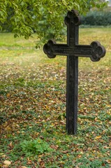 Old iron cross standing in cemetery during autumn