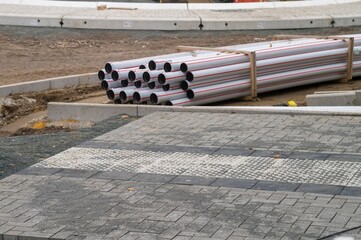 Construction site showing tactile paving, pipes and dirt road during roadworks