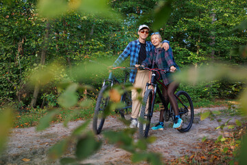 Obraz premium Portrait of happy young man and girl with bicycles in the forest