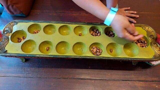 Congklak: Traditional Indonesian Mancala Game"** Congklak is a two-player mancala game where players collect seeds in home holes through strategic moves. The game ends when one side is empty.