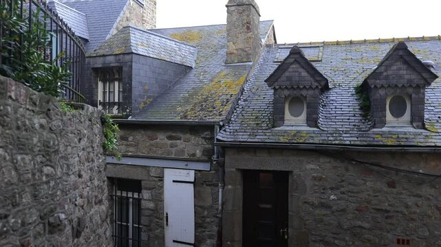 Detailed view of the facades of ancient stone buildings on the grounds of Mont-Saint-Michel Abbey, showcasing historic charm in France.