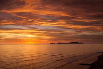 Obraz premium As the sun sets over San Lorenzo Island, the view from Miraflores becomes pure magic .The island silhouettes against a sky ablaze with color, while the ocean whispers of infinite horizons. 