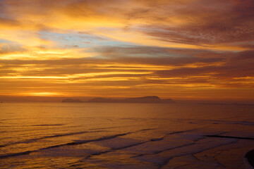 Obraz premium As the sun sets over San Lorenzo Island, the view from Miraflores becomes pure magic .The island silhouettes against a sky ablaze with color, while the ocean whispers of infinite horizons. 