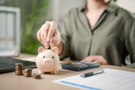 finance, investment, income, piggy bank, insurance, invest, investor, financial, loan, wealth. A woman is putting coins into a piggy bank. Concept of saving money and being financially responsible.