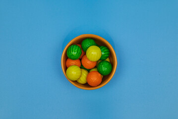 Chewing gum balls of different colors in shiny earthenware containers with a homogeneous colored background for placing text