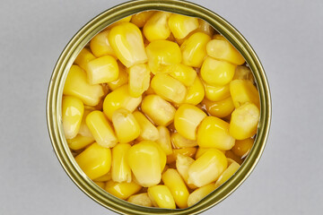 Very colorful canned corn kernels, in a zenithal or top shot with a gray background, concentrated product