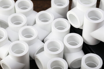 White plastic plumbing pipe fittings in various shapes stacked together. Top view.