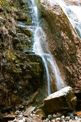 Serene waterfall cascades down moss-covered rocks, surrounded by the vibrant colors of autumn foliage.