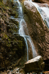 Obraz premium Serene waterfall cascades down moss-covered rocks, surrounded by the vibrant colors of autumn foliage.