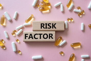 Risk Factor symbol. Concept word Risk Factor on wooden blocks. Beautiful pink background with pills. Medicine and Risk Factor concept. Copy space