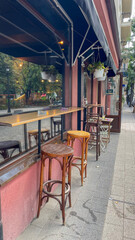 Charming urban cafe with a street-side view, featuring classic high stools and wooden countertops under a protective awning, ideal for city lifestyle and leisure themes in marketing