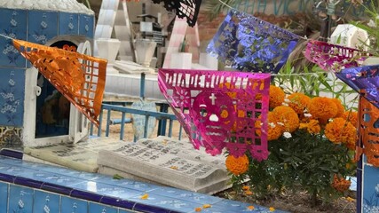 Traditional Mexican papel picado flags and marigold flowers decorating grave on Day of the Dead - Powered by Adobe