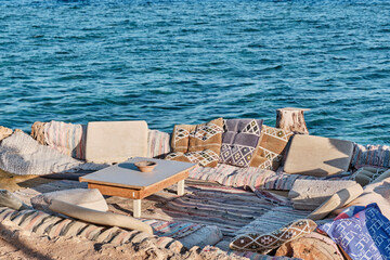 A bright outdoor seating area near the Red Sea with elements of traditional Bedouin decor