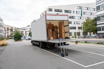 White empty delivery truck with tailgate open in front of an office building. Copy space.
