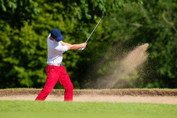 Un golfeur qui tape la balle dans un bunker