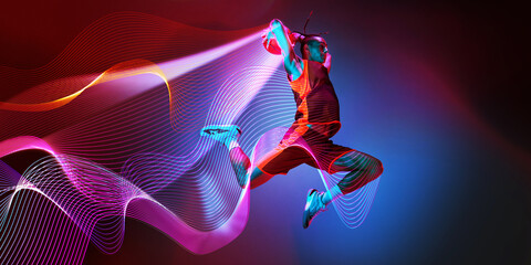Dynamic image of young man, basketball player in motion during game against dark gradient background with abstract neon lines elements. Concept of sport, competition. Creative banner, ad. Modern art