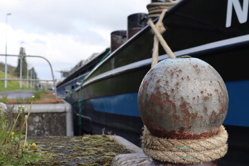 The boat is sucured to the dock with a rope tied to a steel mooring boarding pole