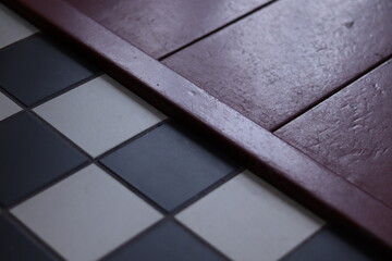 Old floor with small black and white tiles and a red wooden floor