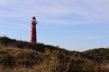 Red lighthouse on the island of Schiermonnikoog, with dunes and marram grass in the foreground